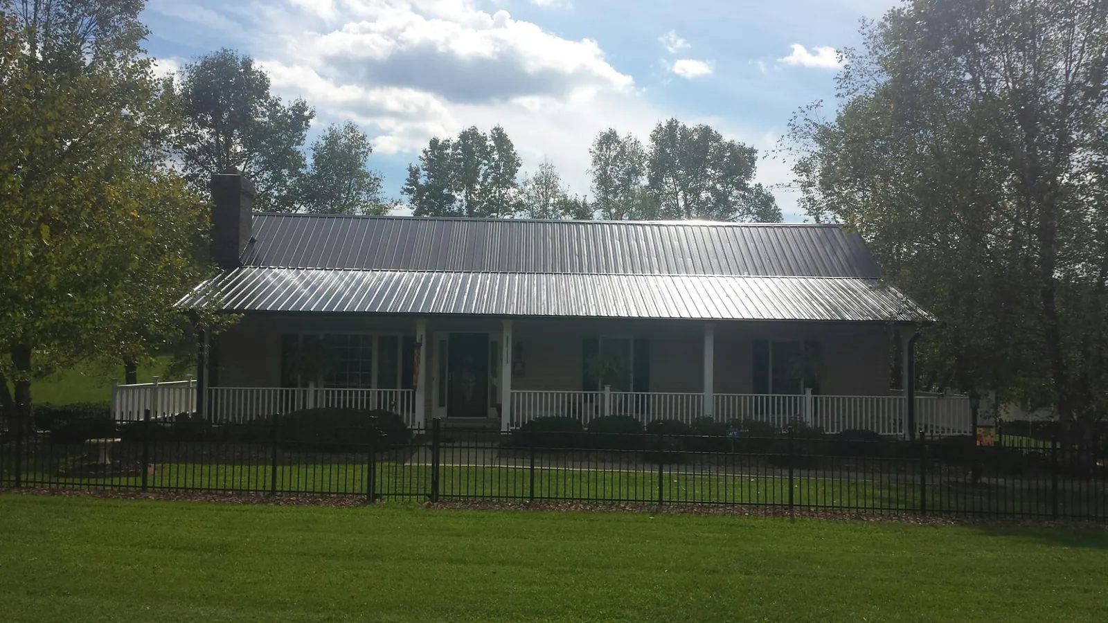 Gray metal roof on a brick ranch with a full width front porch — Gutter Guard Installation work by our crew in Tariffville