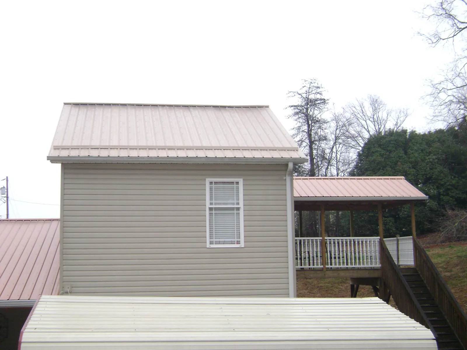 Tan metal roofs on a two story addition and attached porch, from a Roof Replacement job in Tariffville